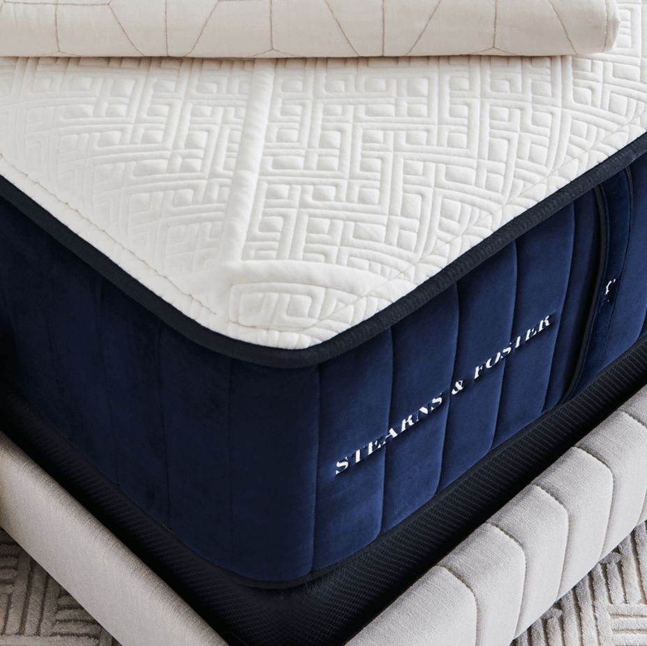 A corner view of a Stearns and Foster mattress on a taupe bed frame.png