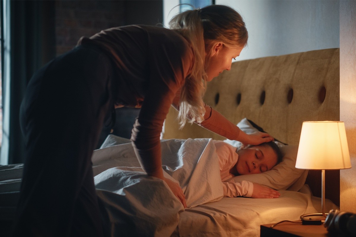 a mother tucking her child into bed
