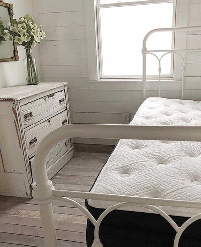 Stearns and foster mattress lying on white metal bedframe in room with white walls and white dresser.jpg