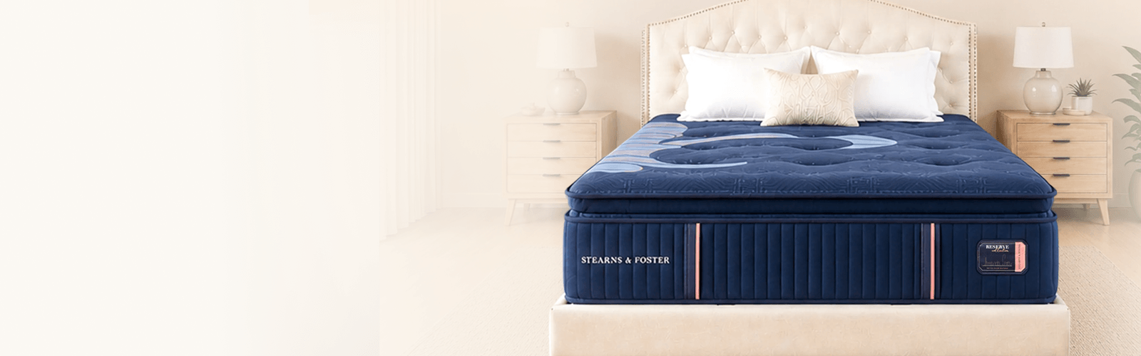 a bare reserve mattress with some pillows against the headboard